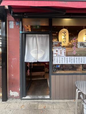 Glass door with black metal frames ahead. Short curtain in front. Push handle on right to open.