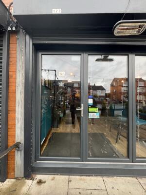 Glass door with grey frame and handle on right. Push to open.