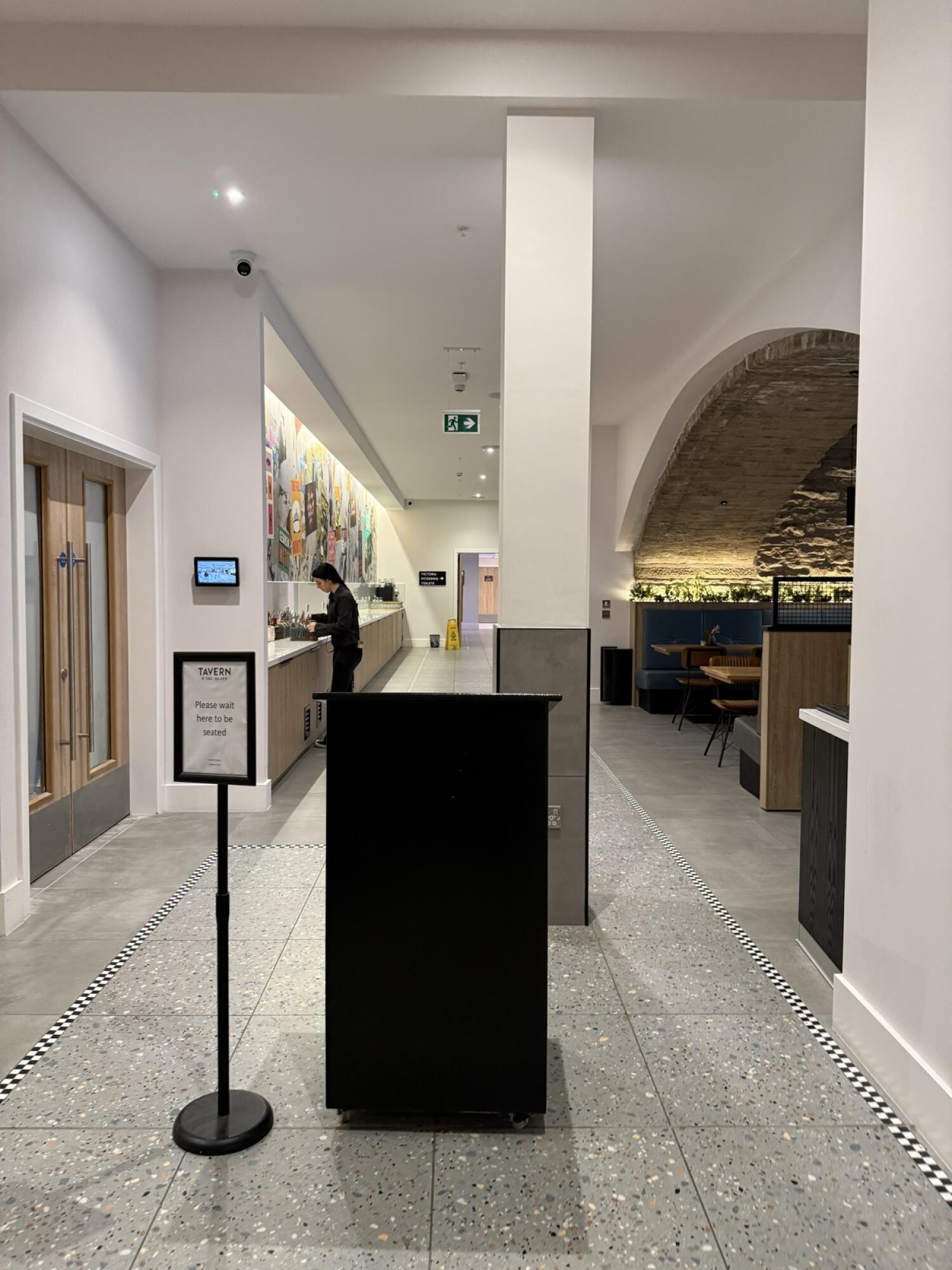From entrance facing straight. Host stand at centre front. Counter with mural along left wall. Booth seating to right under arched stone ceiling.