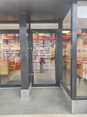 From sidewalk facing venue. Grey framed glass door ahead. Pull silver handle on left to open.