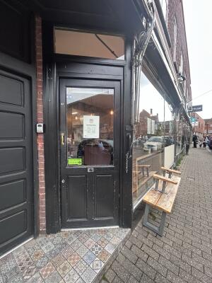 Glass door with black wooden frames ahead. Push handle on left to open.