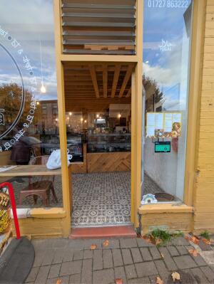 Glass door with yellow metal frames ahead. Push handle on left to open.
