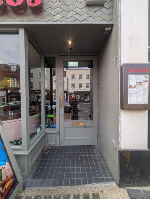 Archway ahead. Glass door with grey frames at back. Pull handle from left to open.