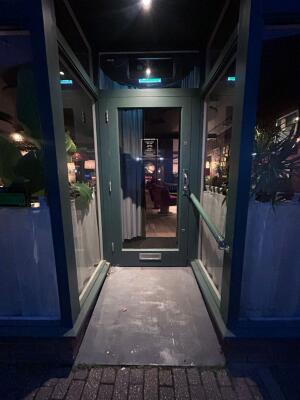 Green frame archway in front. Handrails along right. Green frame glass door at back. Silver handle on right. Pull to open.