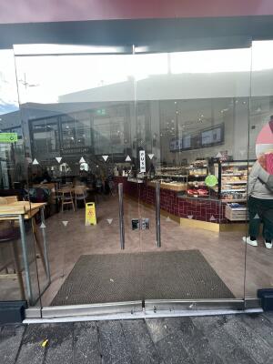 Glass double door with metal handle in centre. Push to open.