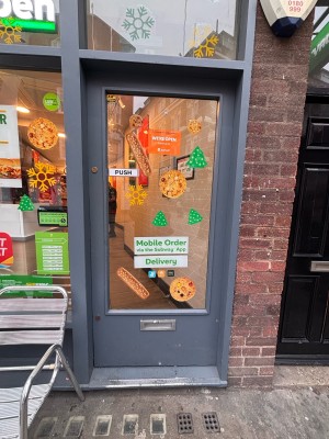 Glassed paneled door with grey doorframe ahead. Push at left to open.