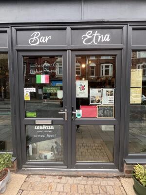Glass double door with grey frame and handle in centre. Push to open.
