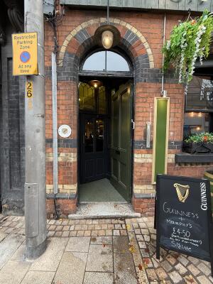 Green wooden door ahead. Push from handle on left to open.