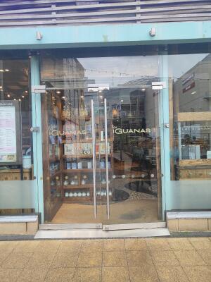 From sidewalk facing venue. Glass door ahead. Pull silver handle in centre to open.