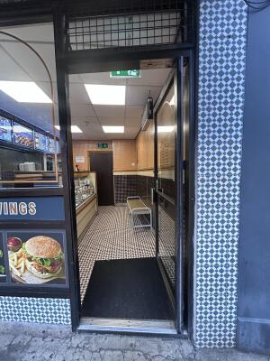 Glass door with black metal frames ahead. Push handle on left to open.