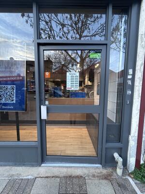 Glass door with grey frames. Push handles from left to open.