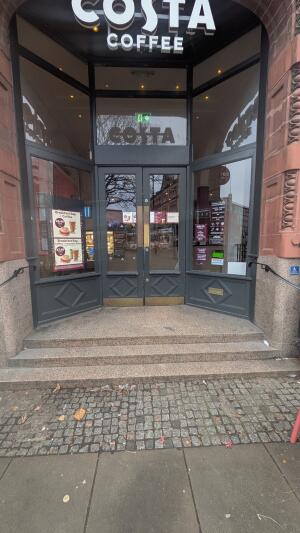 Glass doors with grey frame. Push handle in center to open. Three steps up to doors. Handrails on both sides.