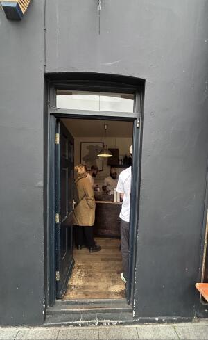 Black wooden door with black frames ahead. Push from right to open.