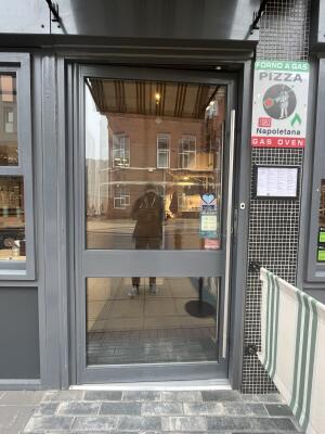 Glass door with a grey frame and handle on right. Push to open.