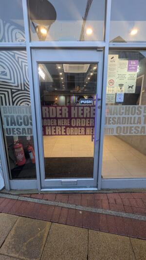 Glass door with metal frame. Push handle on right to open