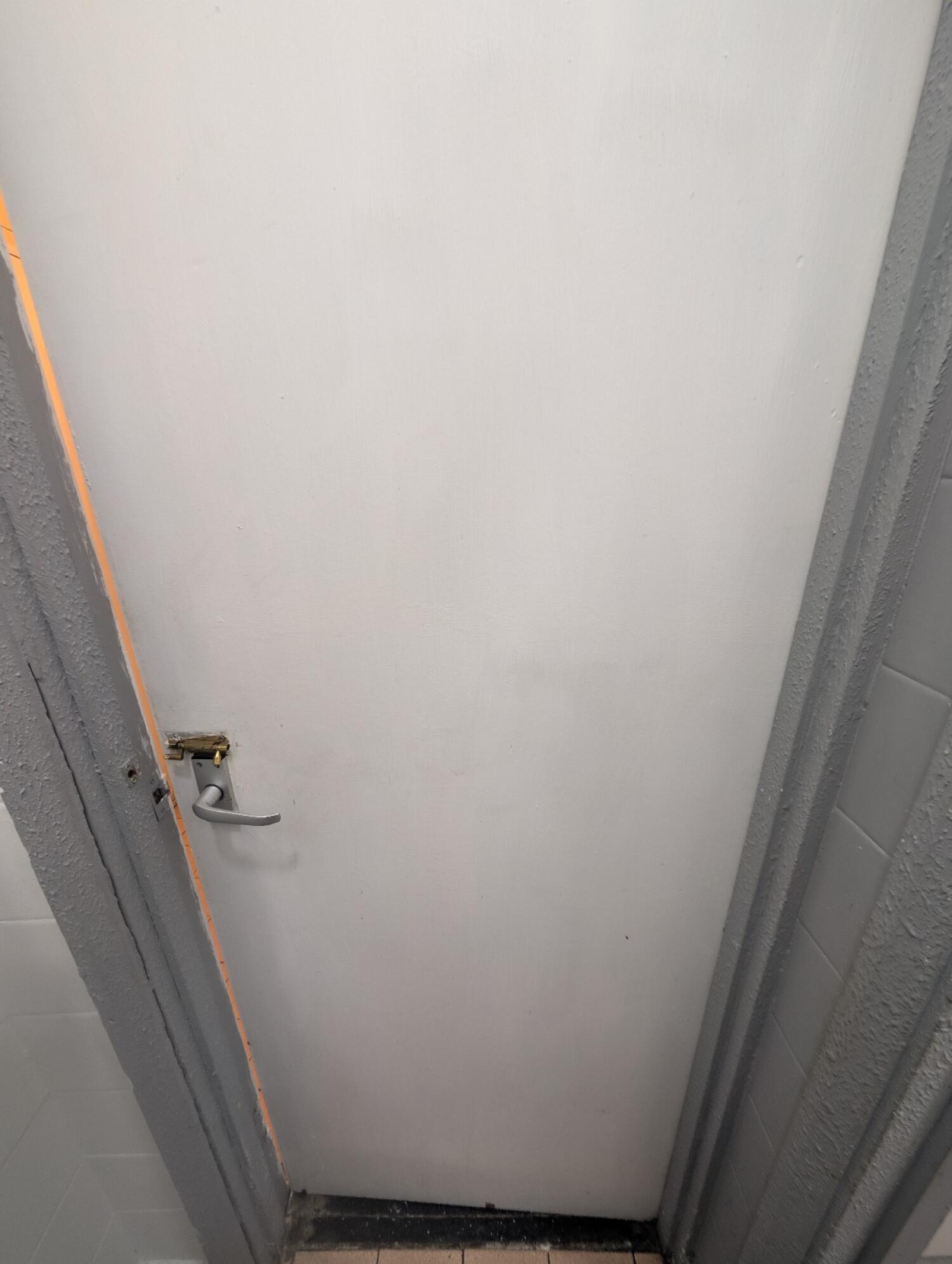 Back of bathroom door. Silver handle on left. Push to open.