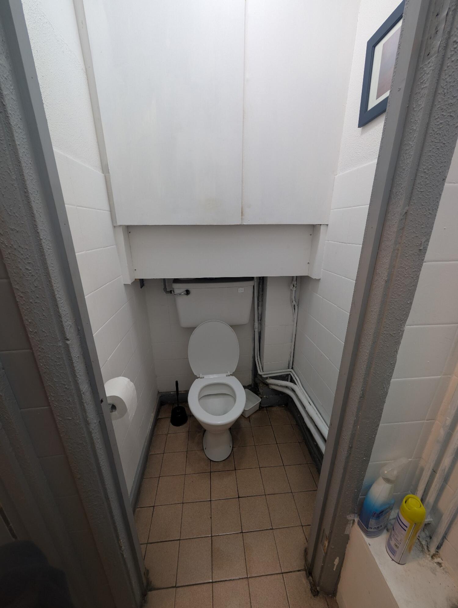 From bathroom door facing left. Grey frame archway in front. Toilet seat at back.