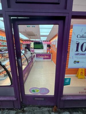 Glass door with purple frame. Push from left to open.