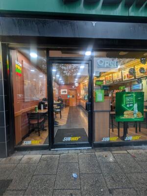 Glass door with black frames ahead. Push handle on right to open.