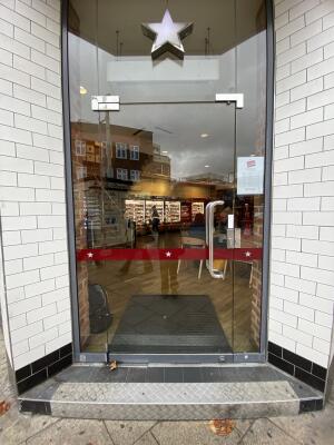 Glass door. Push silver metal handrail from right to open.