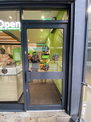 Grey framed glass door. Push from left to open.