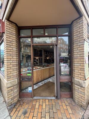 Glass door with brown metal frames ahead. Push handle on left to open.