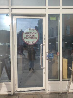 White framed glass door ahead. Push silver handle on right to open.