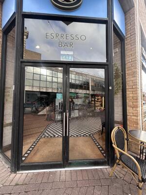 Glass doors with black metal frames ahead. Push handle in center to open.