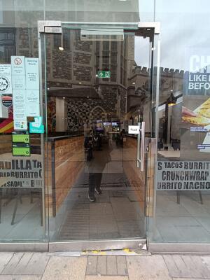 Single glass door ahead. Push silver handle on right to open.