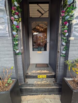 Archway in front. White frame glass door behind.  Silver handle on right. Pull to open.