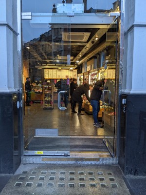 Glass doors with metal handles in centre. Push to open.