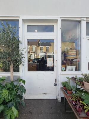 White door with half glass panel ahead. Push door to open. Planters on both sides.