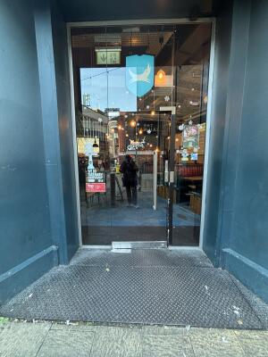 From sidewalk facing entrance. Glass door ahead. Pull handle to open outwards.