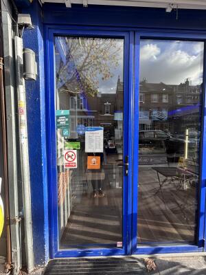 Glass door with blue metal frames ahead. Push handle on right to open.