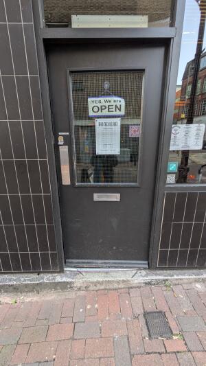 Black metal-framed glass door. Push from metal plate on left to open.