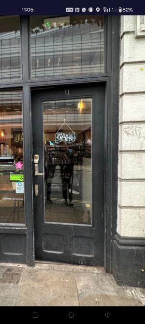 Black wood-framed glass door. Push from handle on left to open.