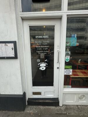 White framed glass door ahead. Push handle on right to open.