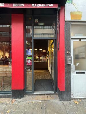 Glass door with black metal frame. Push from handle on left to open.