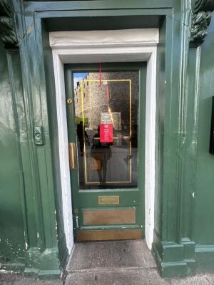 Green frame wooden door in front. Gold handle on left. Push to open.