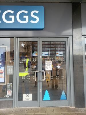 Glass door with grey metal frame ahead. Push from handle at centre to open.