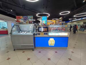 From pathway facing venue. Counter in center. Food display along both sides.