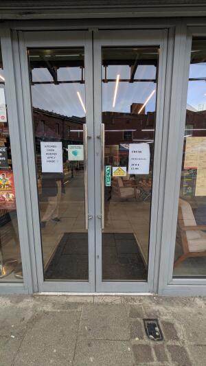 Grey metal-framed glass doors. Push from metal handles at centre to open.
