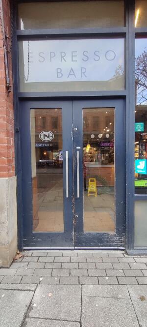 Glass doors with blue, wooden frames. Push metal handles in middle to open.
