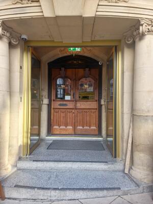 Double glass door with gold frame ahead. Push from handle at centre to open.