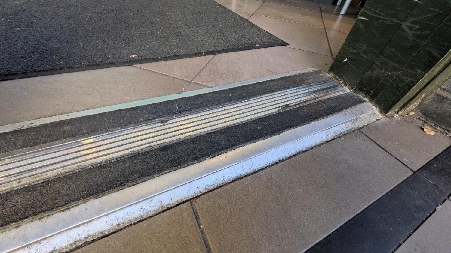 Small bump at foot of door. Doormat inside after bump.