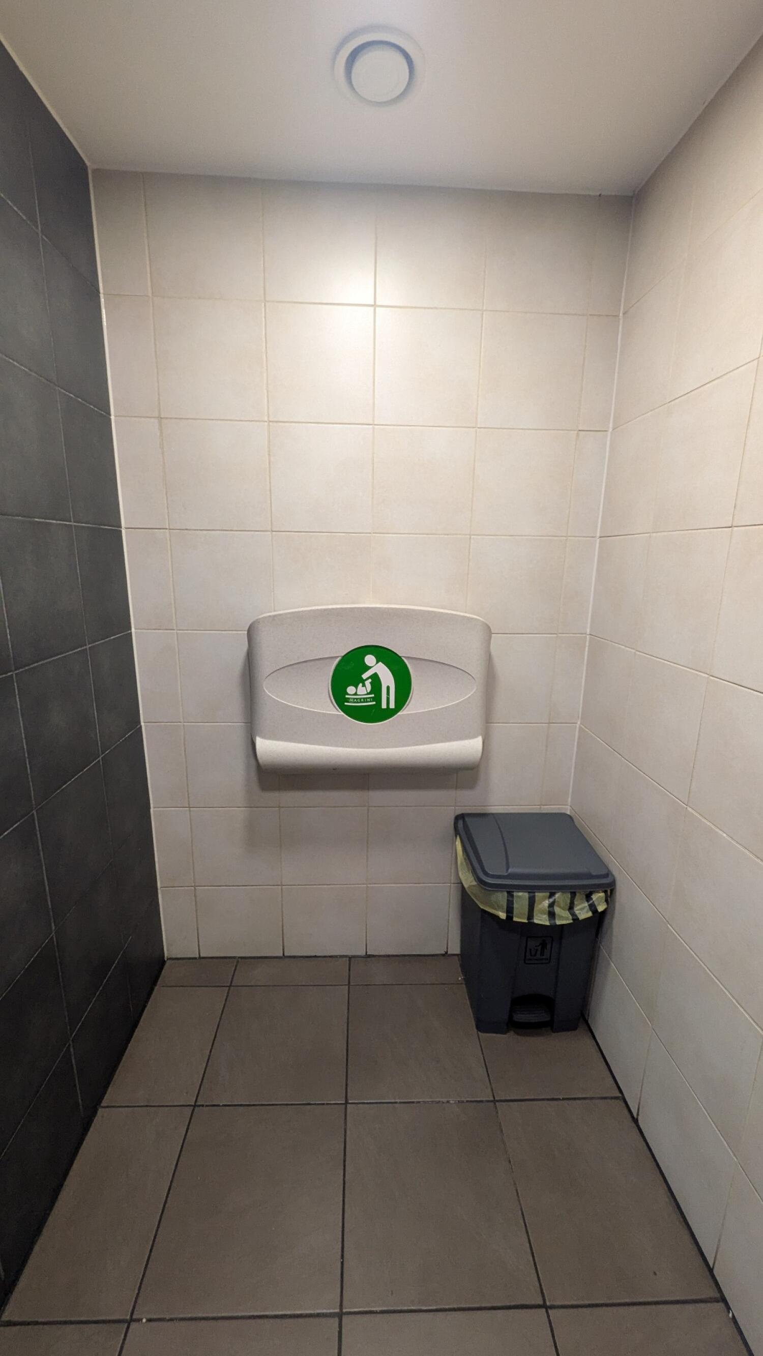 From first door facing left. Baby changing station on back wall. Bin on right below.