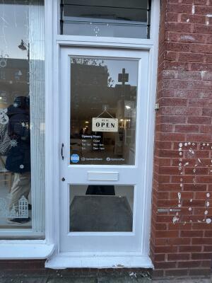 White wood-framed glass door. Pull from handle on left to open.