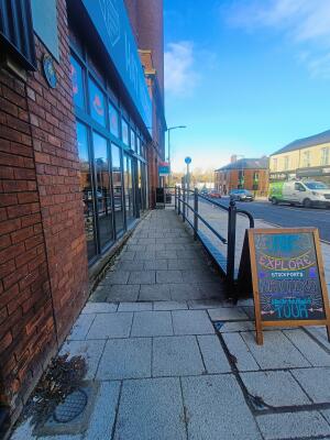 From left of venue facing right. Ramp leading up to venue door. Hand rail along right. A-frame board on right.