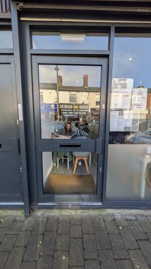 Black metal-framed glass door. Push from handle on right to open.
