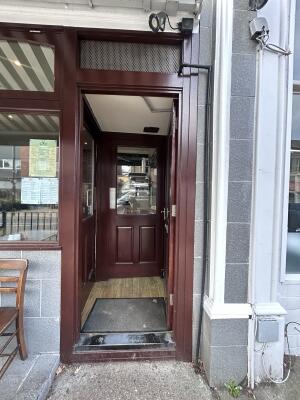 Brown wooden door with brown frames ahead. Push handle from left to open.